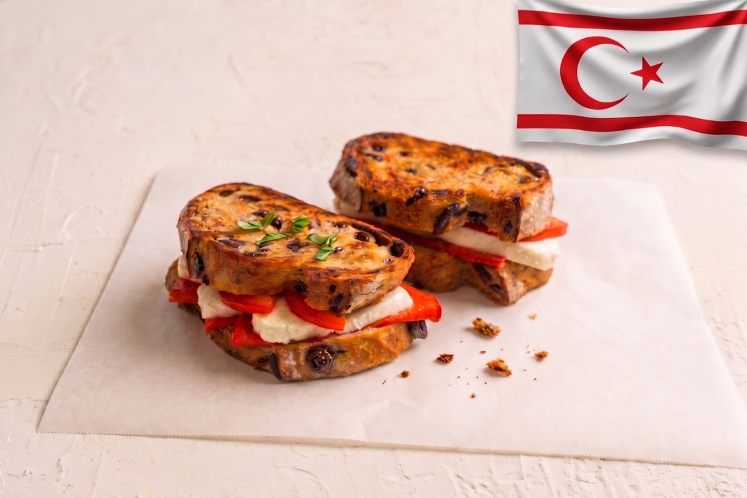 Two grilled sandwiches with tomatoes and cheese on a white surface, with a flag in the background.